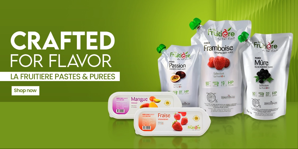 Assorted fruit spreads on a marble counter against an orange backdrop, featuring Durra apricot and strawberry jams with St. Dalfour jars.